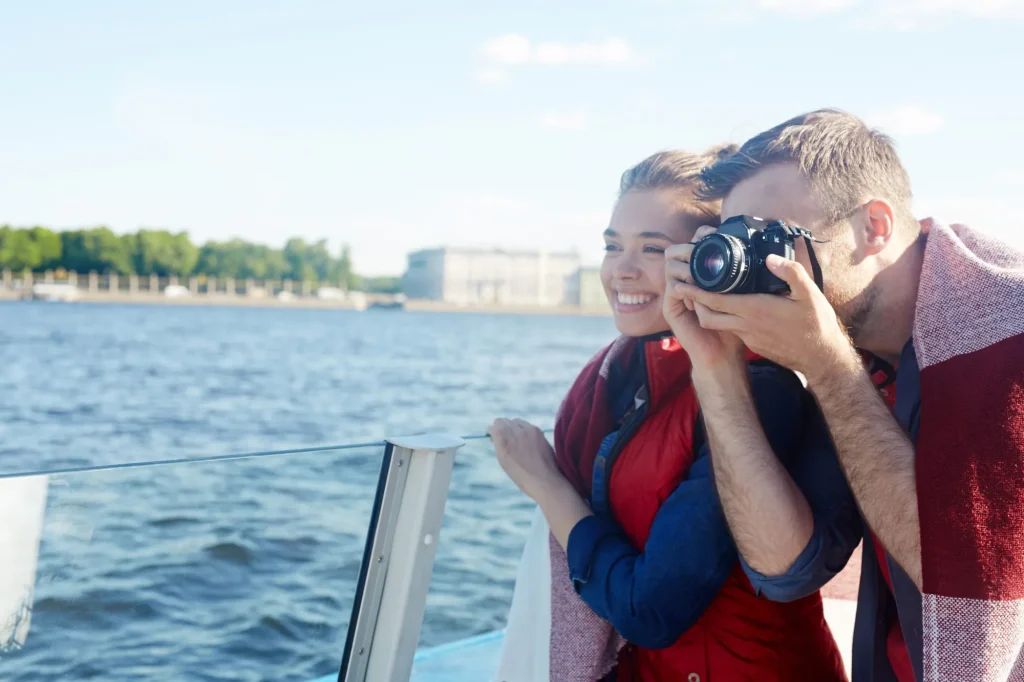 Mladý muž fotografující památky na řece během plavby se svou přítelkyní nebo manželkou